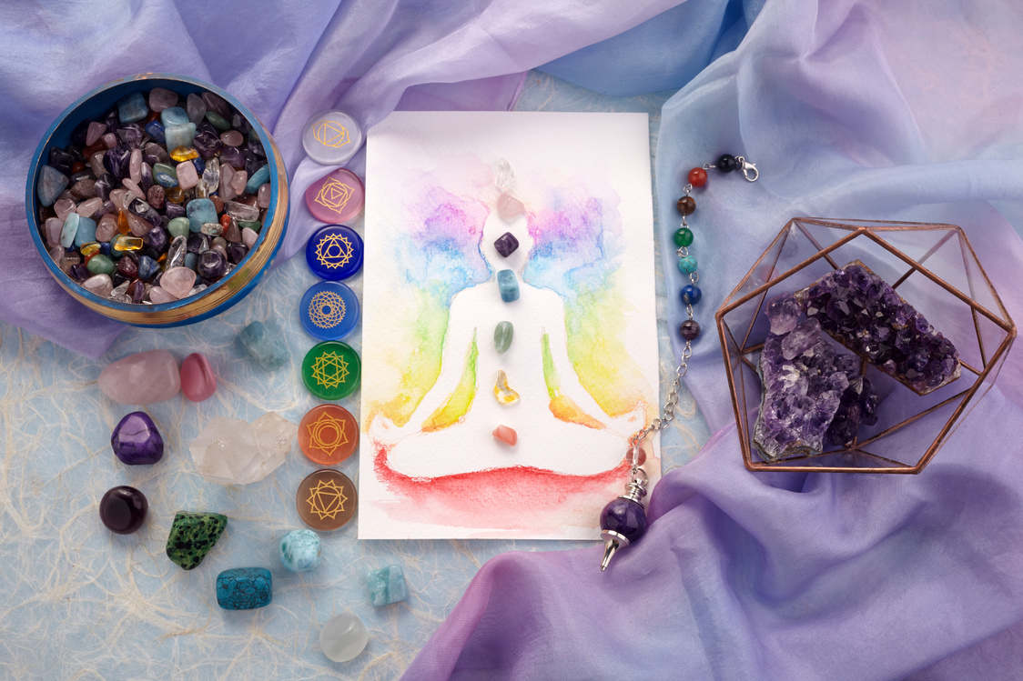 Natural crystals and pendulum on pastel silk background. Reiki background with card.